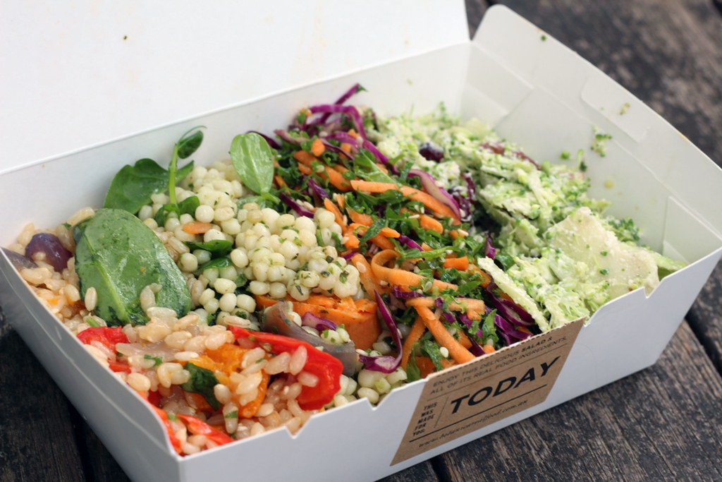 Takeaway salad box with food inside with lid open